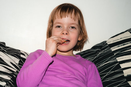 Girl sits on the sofa and eats dried apples