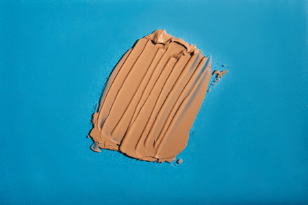 Swatch of brown foundation on blue backgroundの写真素材
