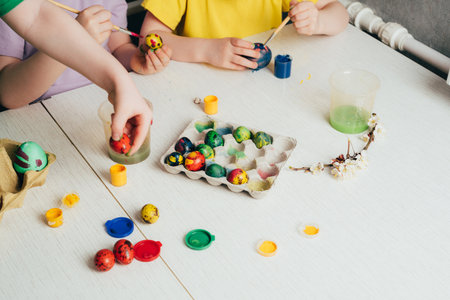 Children's hands that paint quail eggs for Easter. Preparing for a happy easter holidayの写真素材