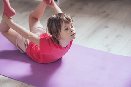 Child performs the exercise gymnastics at home on a mat. home workouts. Health and sports. copy spaceの写真素材