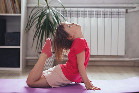 Child performs the exercise gymnastics at home on a mat. home workouts. Health and sportsの写真素材