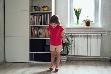 Child warms up before training at home. girl stands on her heelsの写真素材