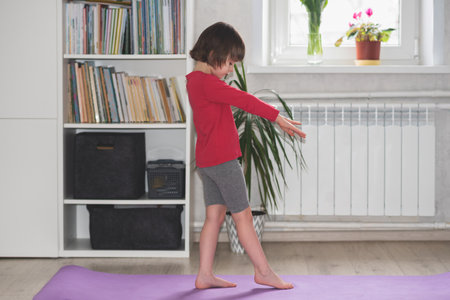 Child girl performs the exercise gymnastics at home on a mat. home workouts. Health and sportsの写真素材
