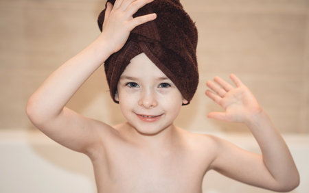 Joyful child in the bathroom with a towel on his head. Children hygiene.の写真素材