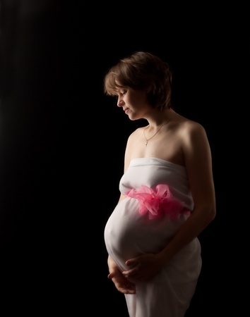 Pregnant woman on the dark background in studioの写真素材