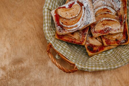 puff pastry puffs with Apple, cinnamon and powdered sugar, in a plate on the wooden table
