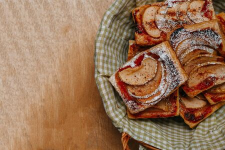 puff pastry puffs with Apple, cinnamon and powdered sugar, in a plate on the wooden tableの写真素材