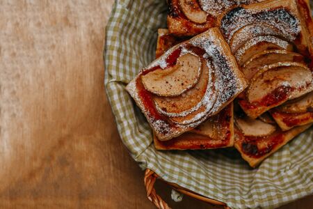 puff pastry puffs with Apple, cinnamon and powdered sugar, in a plate on the wooden table