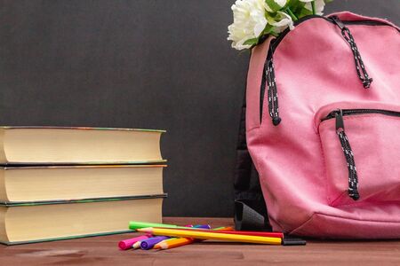 preparing for school, on the table textbooks, pink backpack, flowers, pencils and markers on the...