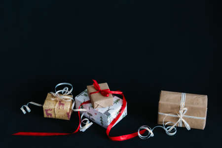 gift boxes Packed in wrapping paper and tied with ribbons for the new year or Christmas lie in a pile on a black backgroundの写真素材