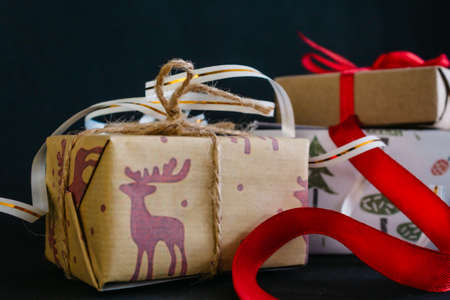 on a black background are Christmas gifts wrapped in wrapping paper and tied with ribbons, a small...
