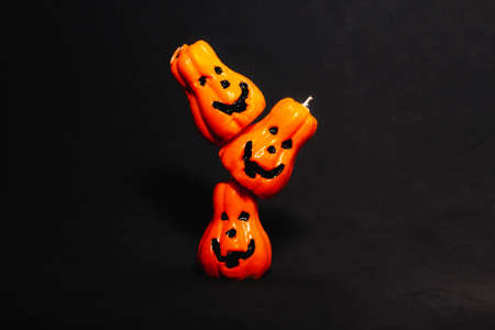 orange pumpkin candles with Jack's face on top of each other on a black background. preparation for...