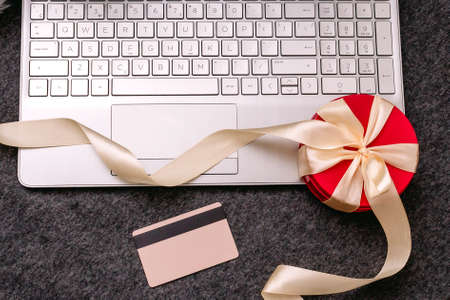 Christmas shopping online with a credit card for the holiday. Laptop with gifts on the table next to fir branches and a garland of lights.の写真素材