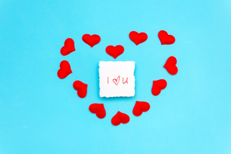 a note on which is written a declaration of love in lipstick, lies on a blue background, surrounded...