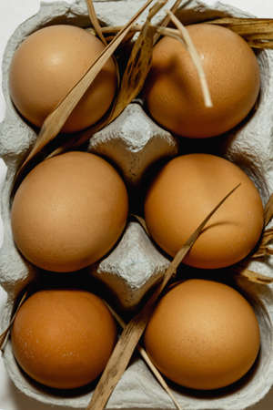 Chicken eggs in a paper tray on a grass straw. top view.
