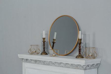 Mantelpiece with stylish decor. Candles in gold candlesticks and a mirror. Retro decor.