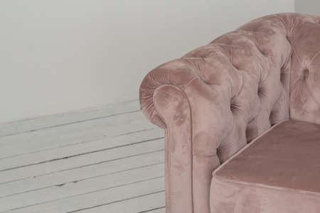 a classic pink sofa sits in a white room on a wooden floor. copy space.