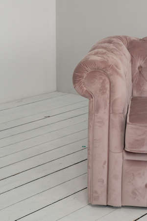 a classic pink sofa sits in a white room on a wooden floor. copy space.
