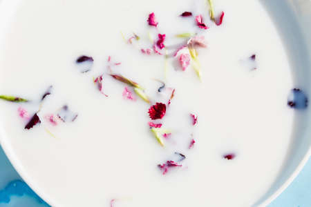milk with flowers in a saucer on a blue background.