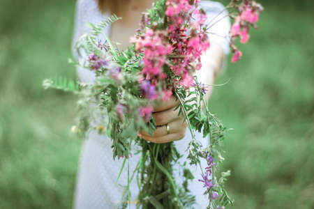 a married woman holds out a bouquet of wild flowers to the camera. The hand of a woman with an engagement ring holds lilac wildflowers. Selective Focus.の写真素材