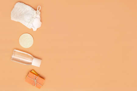 Bathroom accessories with zero waste sponge, bars of solid soap, cosmetic bottle on a beige...