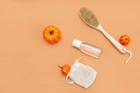 Autumn beauty season still life on a beige background. Small pumpkins, a body brush, liquid in a...