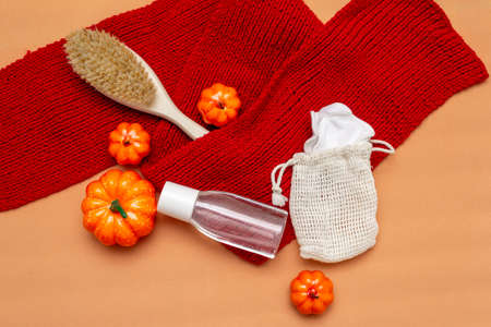 Makeup remover, brush and natural reusable sponges in a bag on a beige background with a red scarf and orange pumpkins. Autumn layout. Top view, flatly.の写真素材