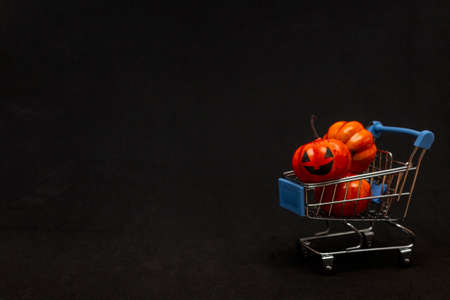 A cart with orange pumpkins on a black background. flat lei on the topic of sale in halloween. copy space.の写真素材