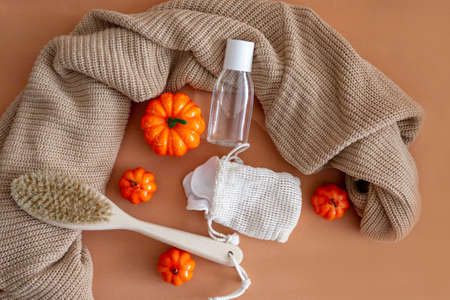 pumpkins, a natural body brush, makeup remover, sponges and a warm sweater on a beige background. Cosmetics for face and body. Autumn layout. Top view.の写真素材