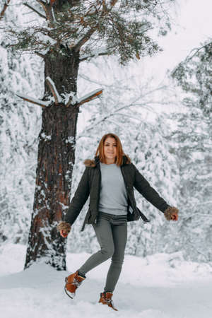 A happy girl with a short haircut walks in the forest after a snowfall and admires the incredible nature. Winter fairy tale in the forest. Christmas holidays, outdoor activities.の写真素材