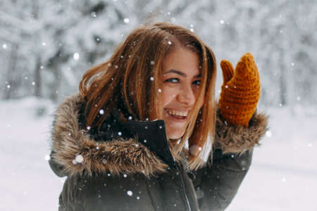 Portrait of a happy girl with a short haircut in mustard mittens in the forest after a snowfall. Christmas holidays, outdoor activities.の写真素材