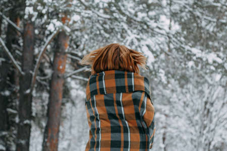 A happy young girl, wrapped in a plaid plaid and basking on a walk in the winter forest. A walk in the Christmas holidays, selective focus.の写真素材