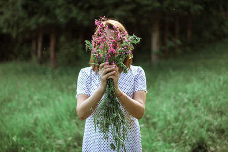 a beautiful girl hidden behind a bouquet of wild flowers. A photo without a person's face