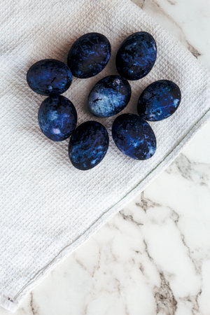 Cosmic colored eggs lie on a white waffle towel on a marble table. Easter eggs on the table. vertical.の写真素材