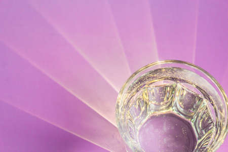 Bizarre patterns from the sun on a lilac table. The sun's rays pass through a glass faceted glass of water.の写真素材