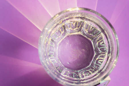 Bizarre patterns from the sun on a lilac table. The sun's rays pass through a glass faceted glass of water.の写真素材