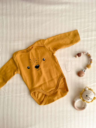 A flat lay with cute newborn baby clothes and eco-friendly accessories on a light sheet in the crib....