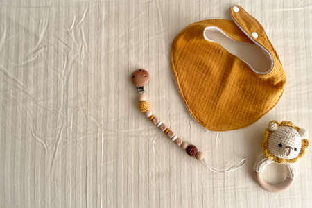 Composition with baby muslin bibs, rattles with a knitted body and chains of wooden beads with a...