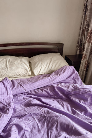 Aesthetic minimalistic bedroom interior design. A bed with a white sheet and pillows, a rumpled lilac blanket.の写真素材