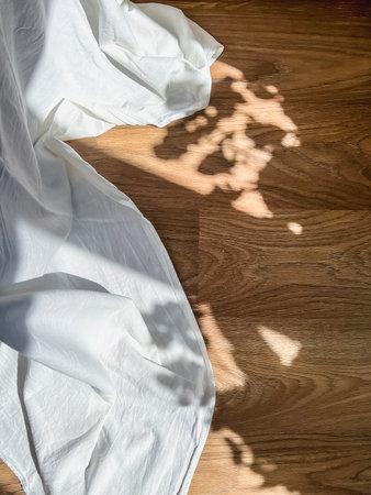 The play of light and shadow on a dark floor next to a white cloth.の写真素材