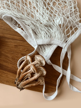Yes, the mushrooms of the mushroom family are lying on a wooden board next to a white string bag on...