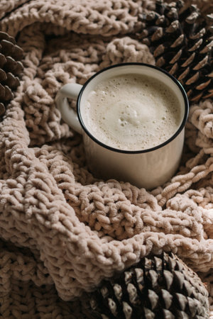 Coffee with milk in a glass mug among the cones on the blanket. Vertical photo.の写真素材