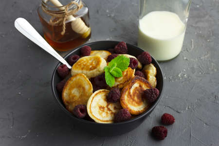 Traditional dutch mini pancakes or poffertjes with raspberry and mint