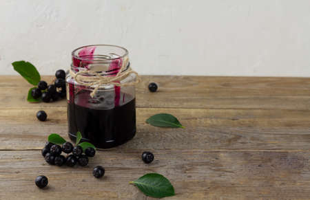 Chokeberry jam and fresh berries on wooden table with copy space