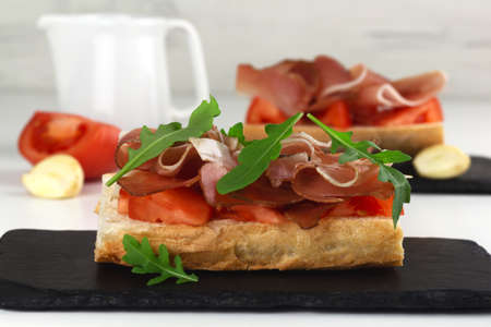 Spanish tapos with hamon, italian bruschetta with proscuitto on a black slateの写真素材