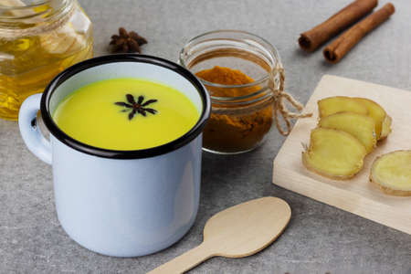 A cup of golden milk, ayurvedic turmeric beverage and ingredients