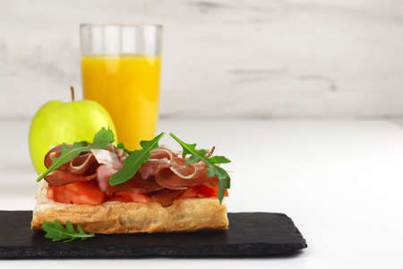 Tapas with spanish hamon or bruschetta with italian proscuitto, orange juice and an appleの写真素材