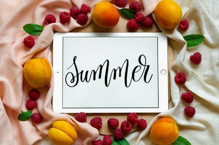 The tablet says the word SUMMER with fresh fruits on the wooden background. Concept of the summer, View from above. Place for text. Copy Space.の写真素材