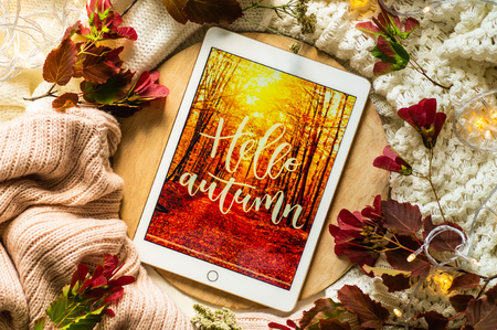The tablet says the word hello Autumn with red leaves and a dais on the wooden background. Concept of the autumn View from above. Copy Space.の写真素材