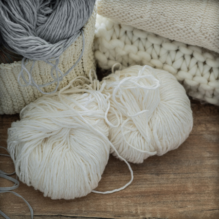 A woven basket with white and gray thread for knitting and knitting needles. White sweaters and yarn for knitting closeup.の写真素材